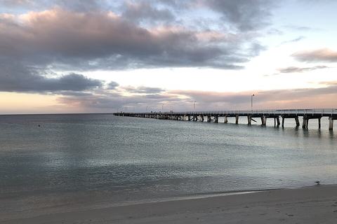 Long jetty reaching into calm water at dusk